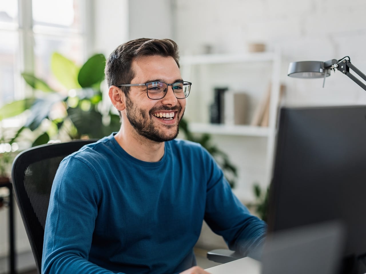 Entwickler lacht am Schreibtisch im Büro von eyvi Digital